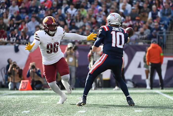 New England Patriots quarterback Mac Jones (10) throws the ball away while Washington Commanders defensive end James Smith-Williams (96) defends during the first half at Gillette Stadium.